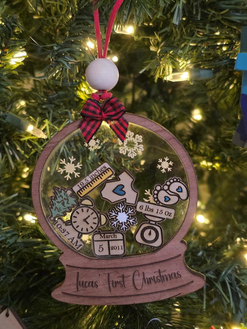 Personalized Christmas ornament with baby milestone details on a decorated tree.