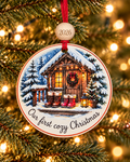 Our First Cozy Christmas ornament with two pairs of winter boots on a snowy cabin porch, 4 inch round wood Christmas ornament with 2026 bead by Bandit Laser