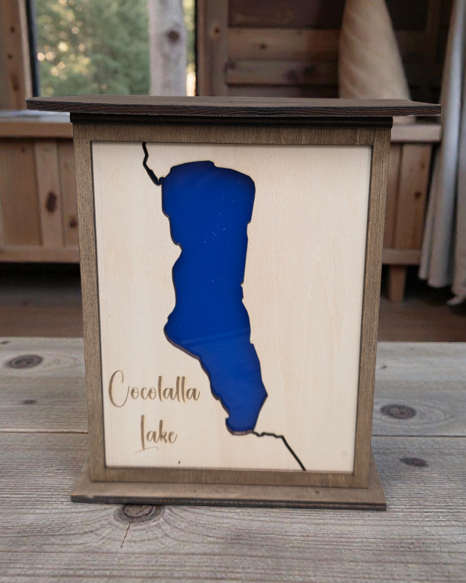 Wooden frame with a blue outline of a lake and 'Cocolalla Lake' text on a wooden surface.