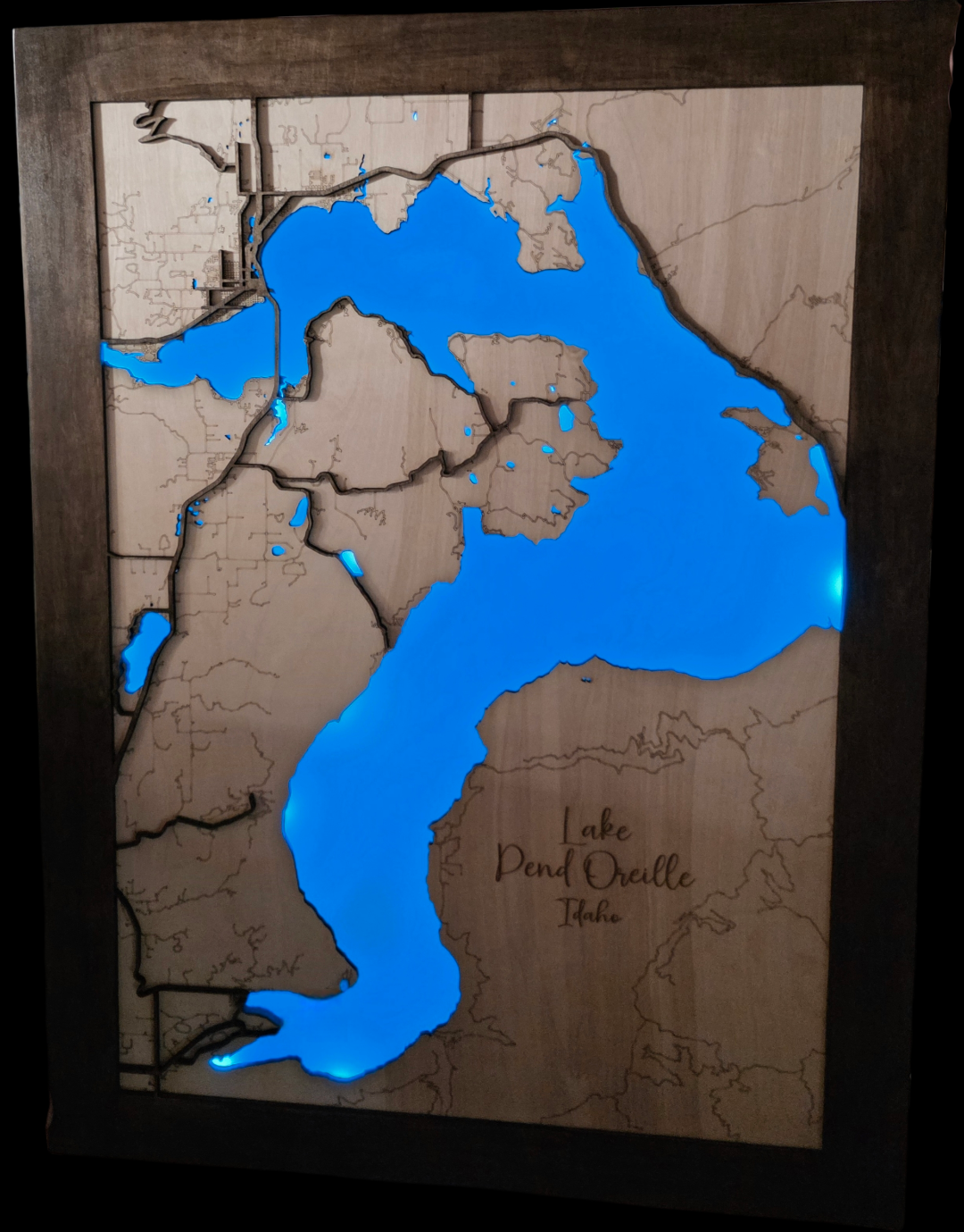 Wooden map of Lake Pend Oreille with blue water and brown land.
