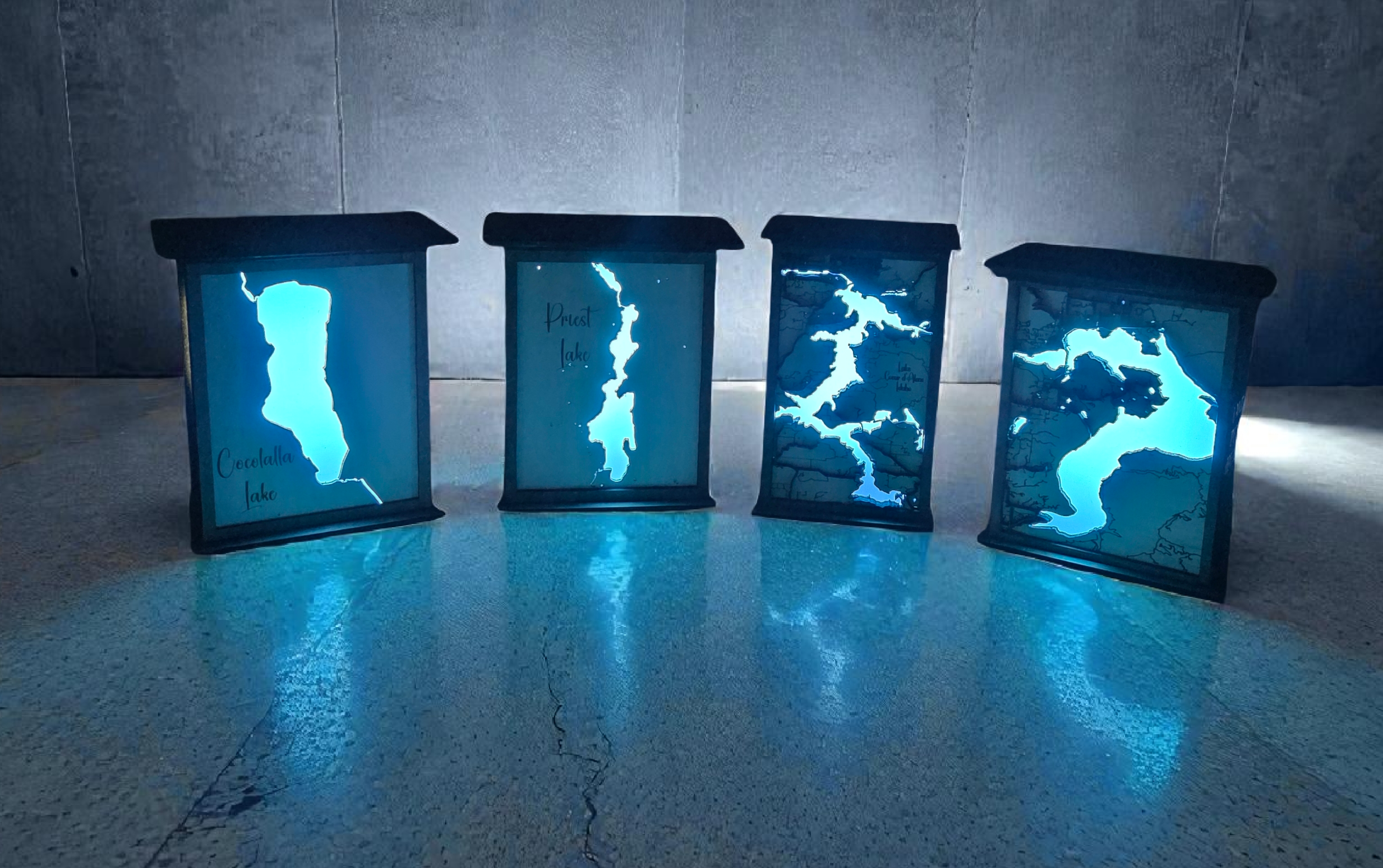 Four glowing blue light boxes with abstract designs on a reflective surface.