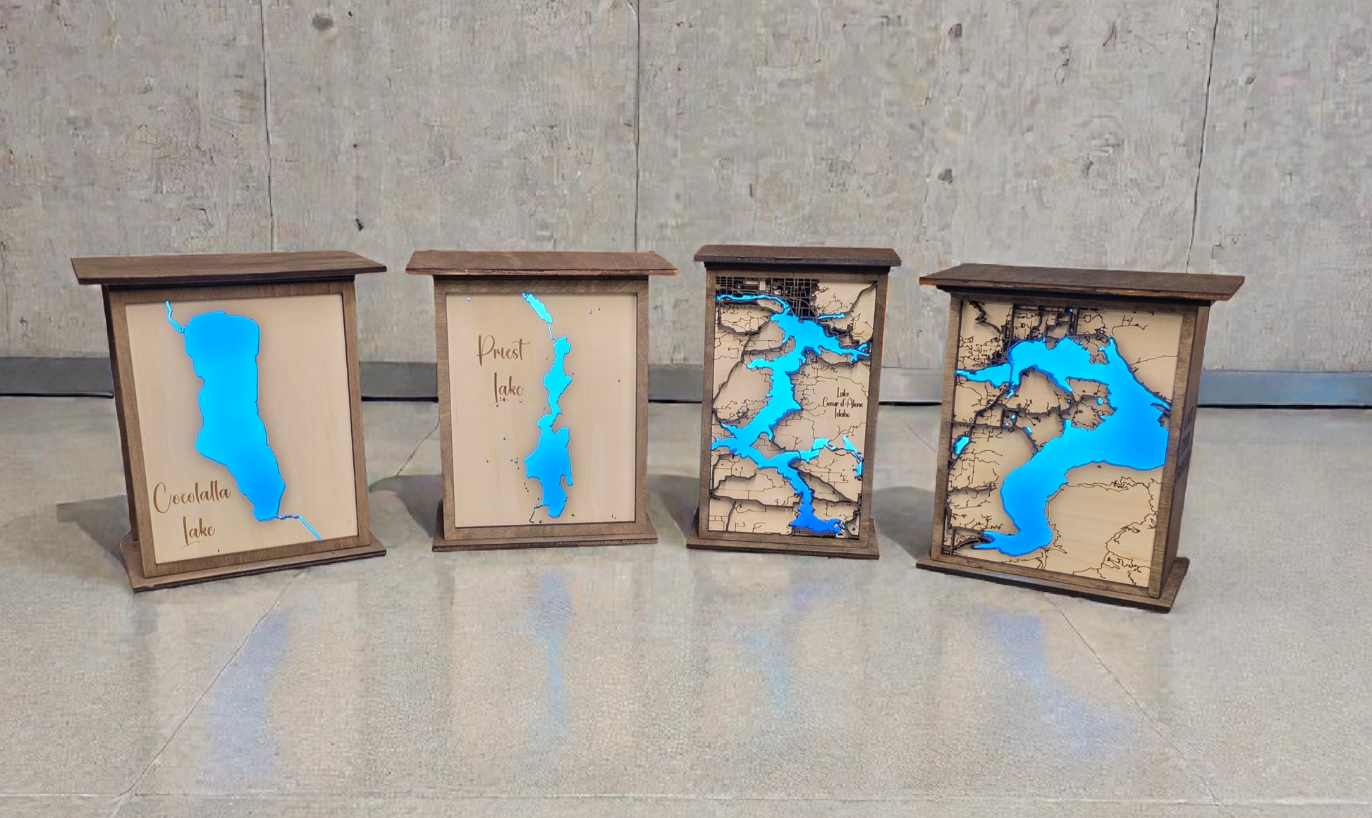 Four wooden panels with blue inset maps on a concrete floor.
