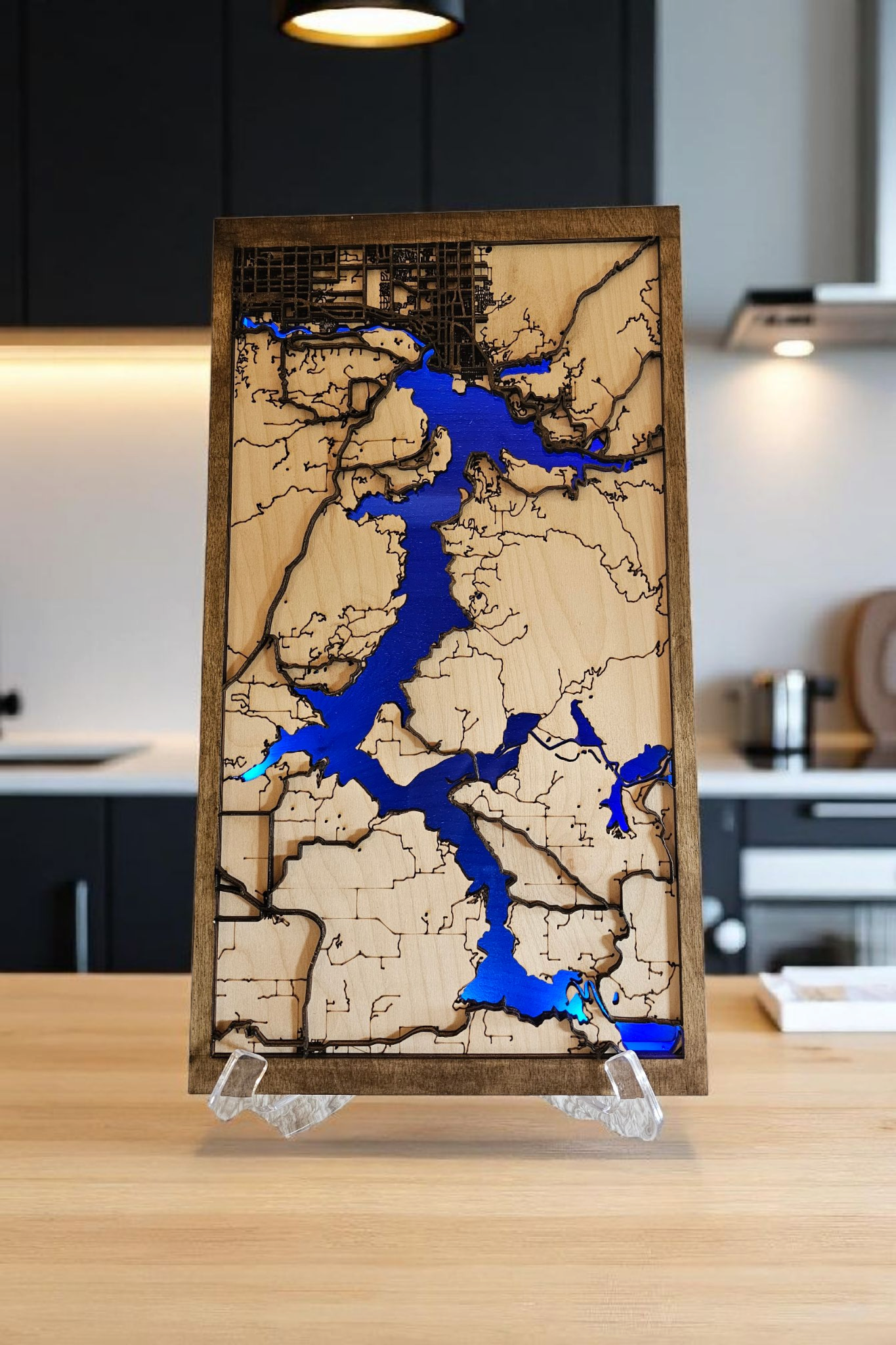 Wooden map with blue water features on a stand in a kitchen setting