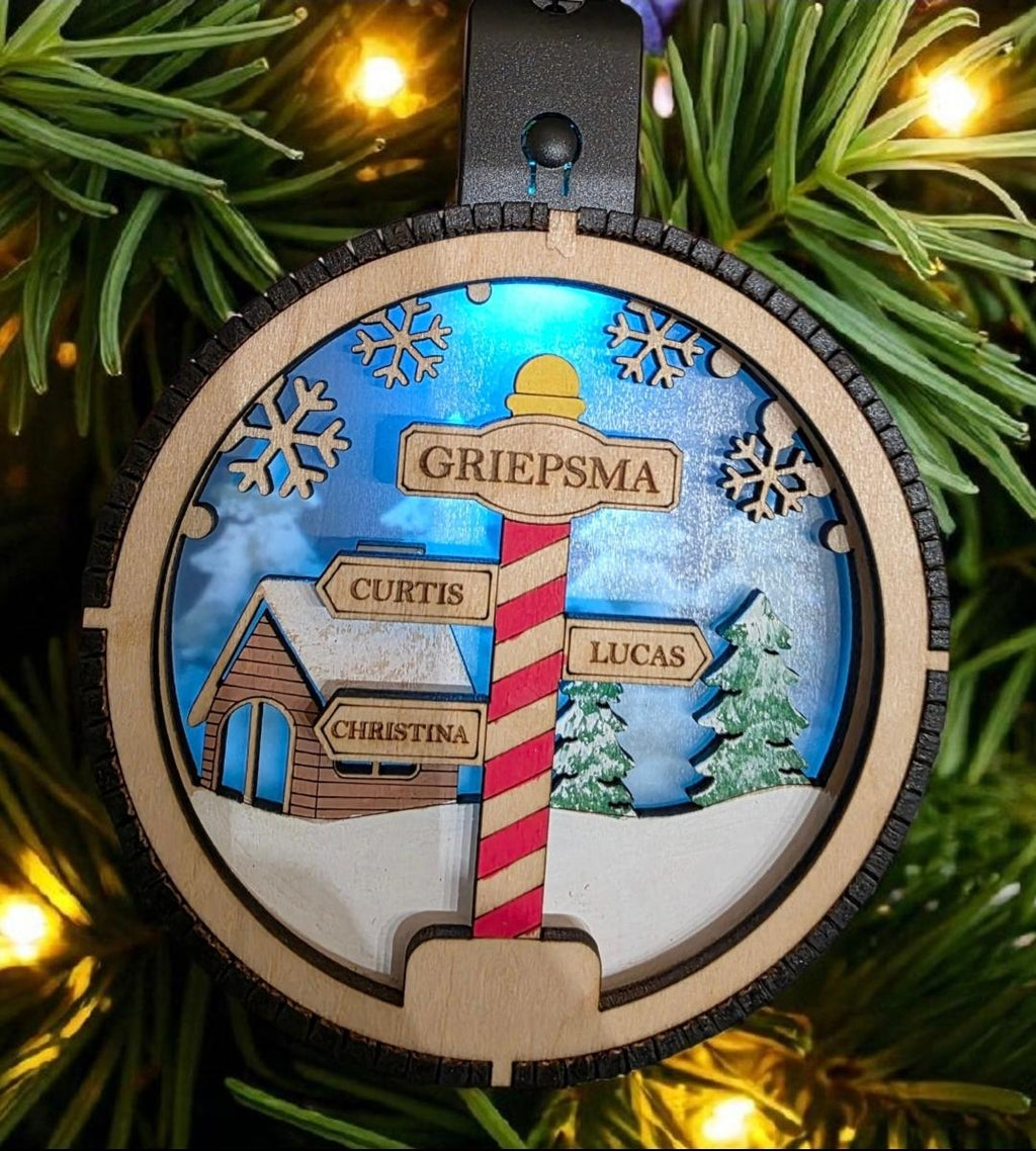 Decorative Christmas ornament with a candy cane sign and family names on a tree.