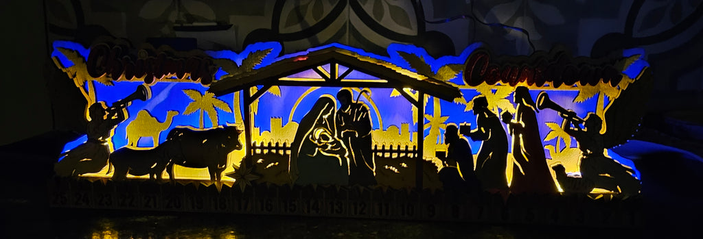 Silhouette nativity scene with Mary, Joseph, and baby Jesus in a manger, surrounded by animals and shepherds.
