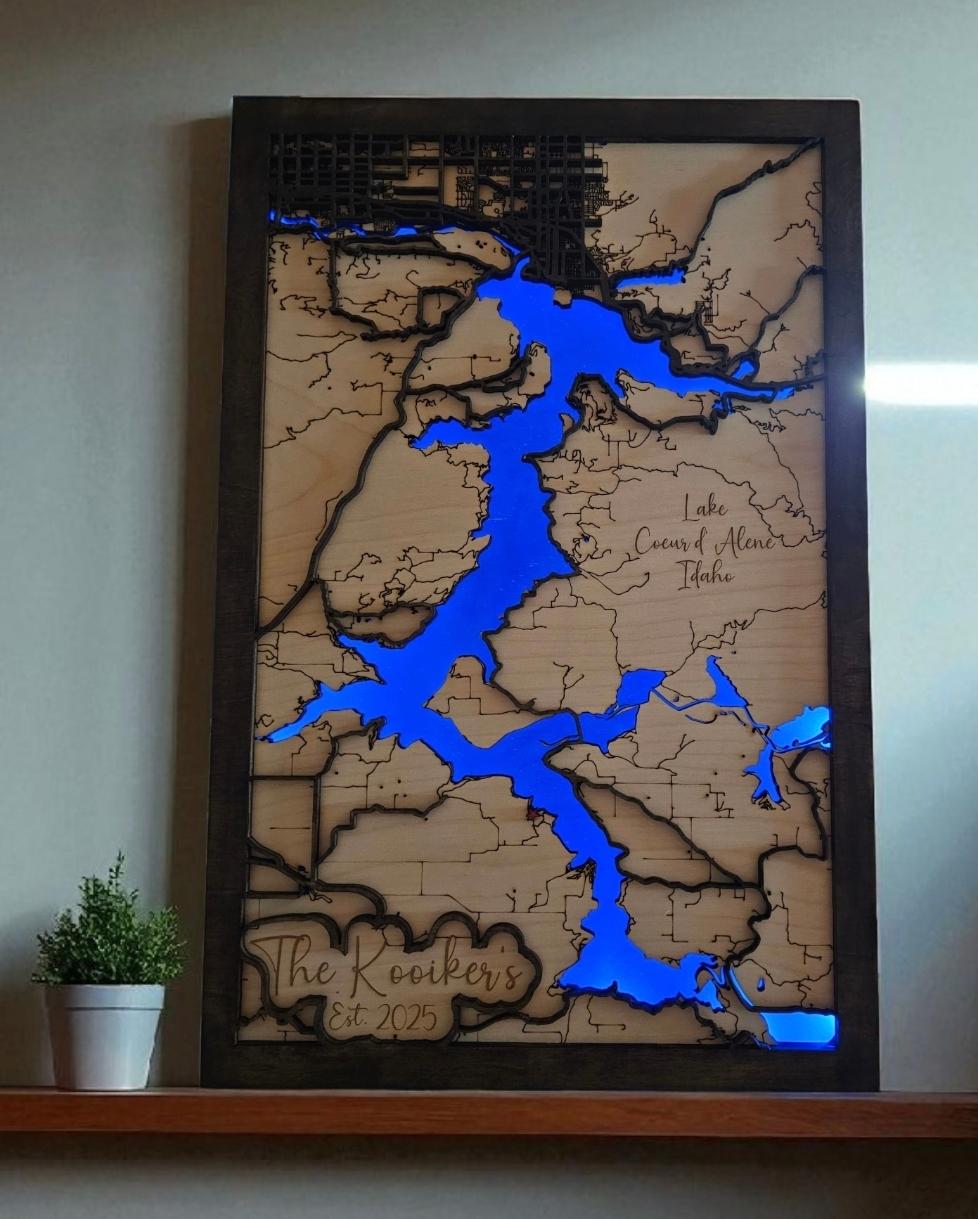 Wooden map with blue water features on a wall, framed by a black border.