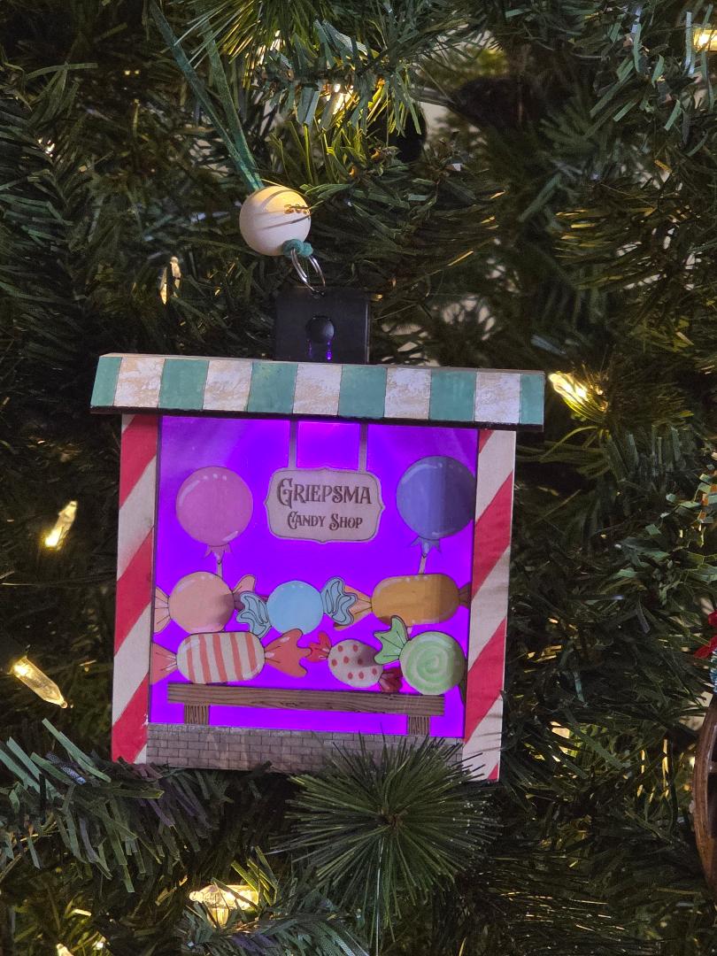 Decorative ornament with candy-themed design on a Christmas tree.