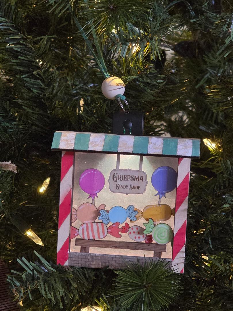 Decorative ornament with candy-themed design on a Christmas tree.