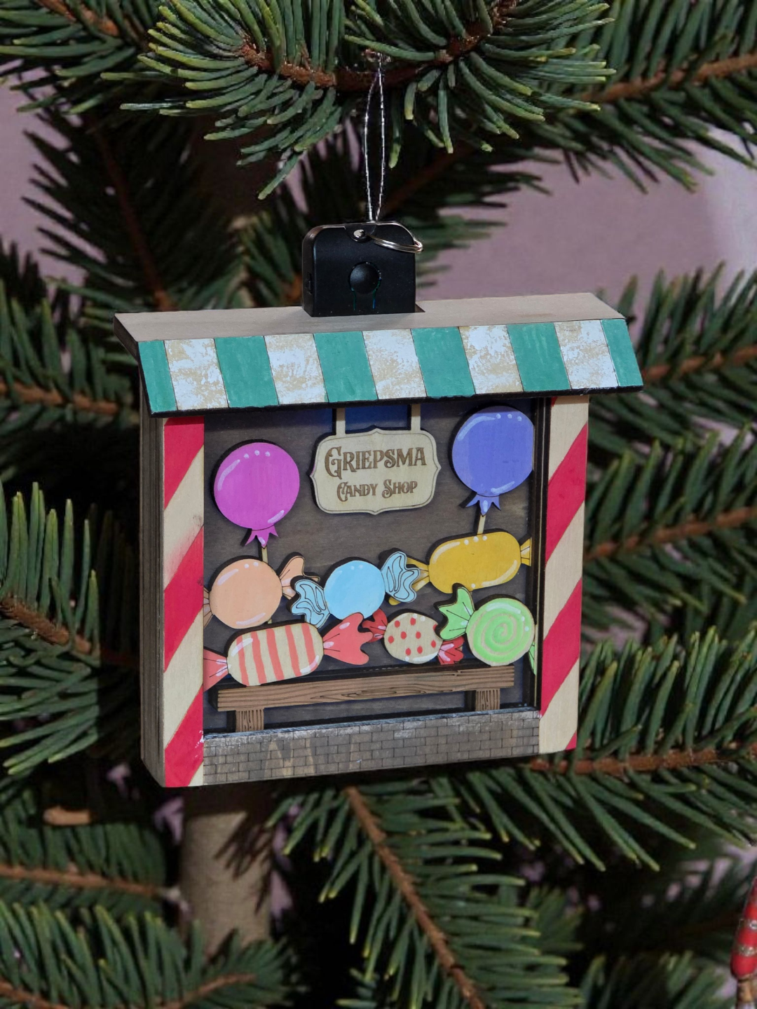 Decorative Christmas ornament with candy-themed design on a tree.