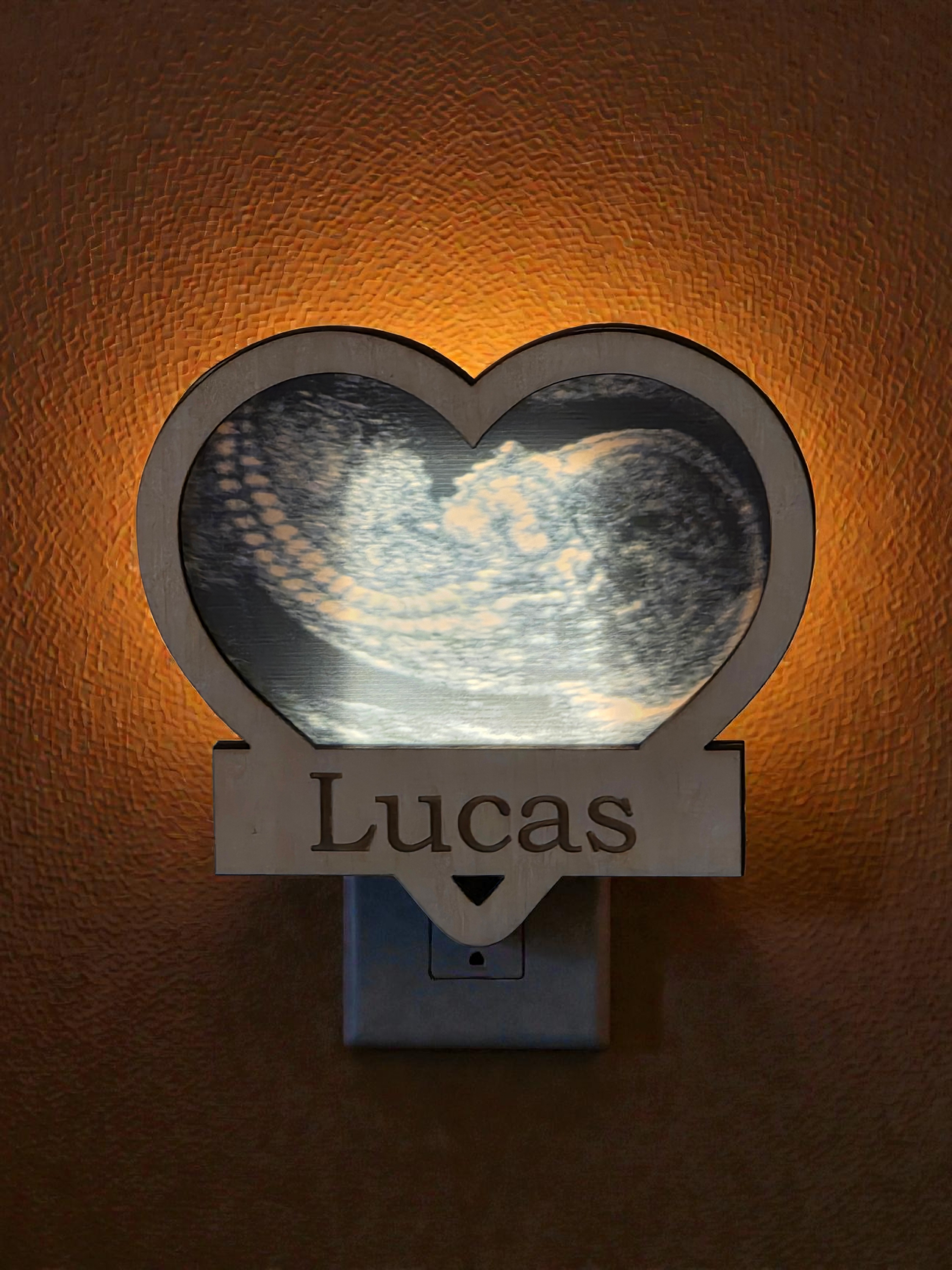 Heart-shaped night light with 'Lucas' engraving on a textured brown background