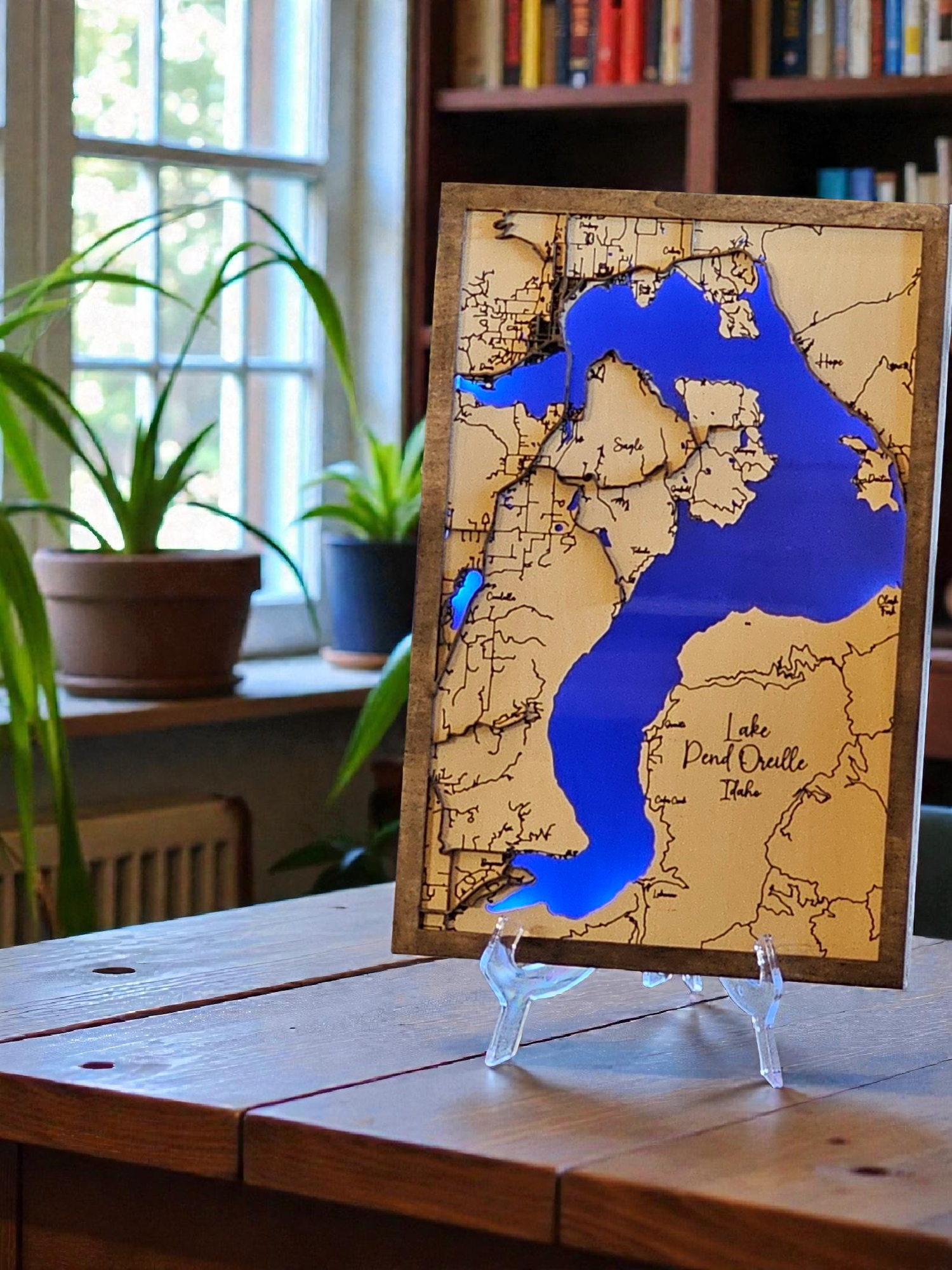 Wooden map of Lake Pend Oreille on a stand with plants and books in the background