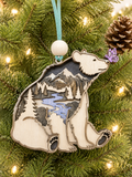 Layered wood bear ornament with mountain river scene and purple butterfly, hanging on a Christmas tree